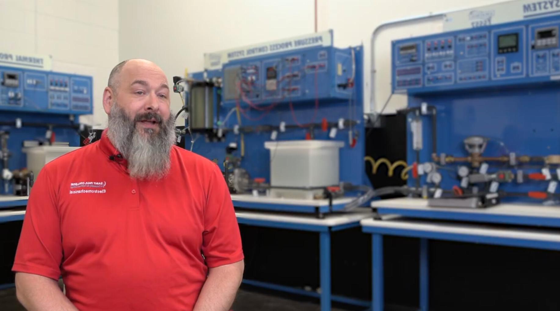 Travis Schachtner in front of electromechanical equipment